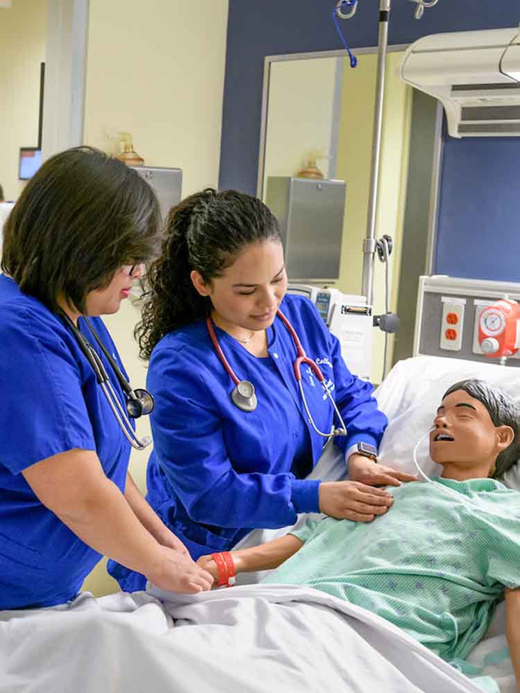 two female nurses providing bedside care to mannequin patient