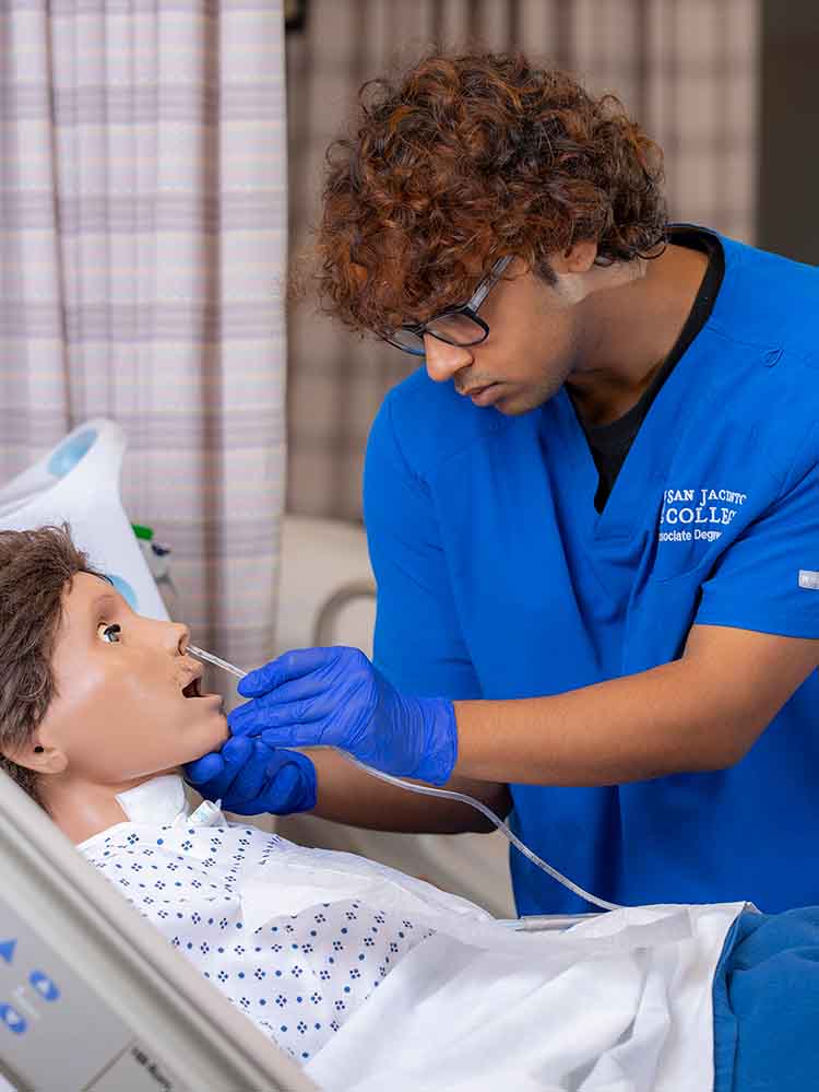 male nursing inserting tube in mannequin patient's nose