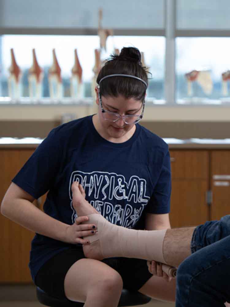 pta wrapping a patient's ankle with safety wrap