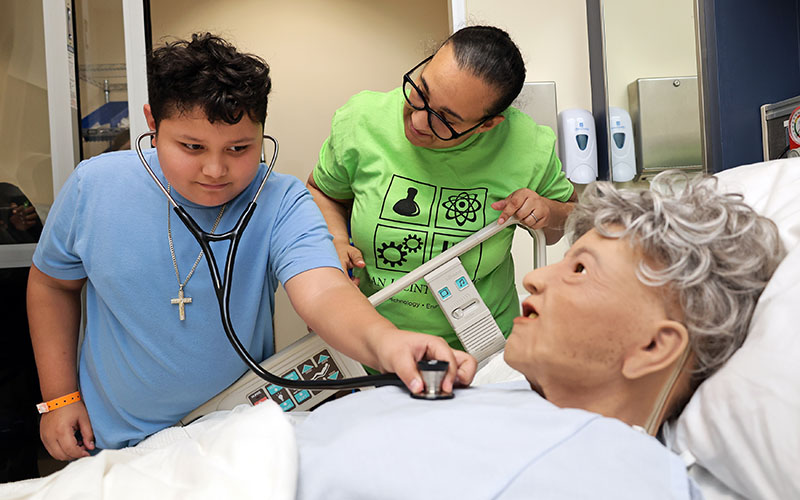 Boy using stethoscope on health science manikin during stem expo